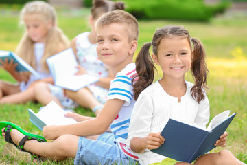 Fototapeta na wymiar Cute little children reading books in park