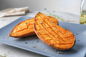 Plate with baked sweet potato on table