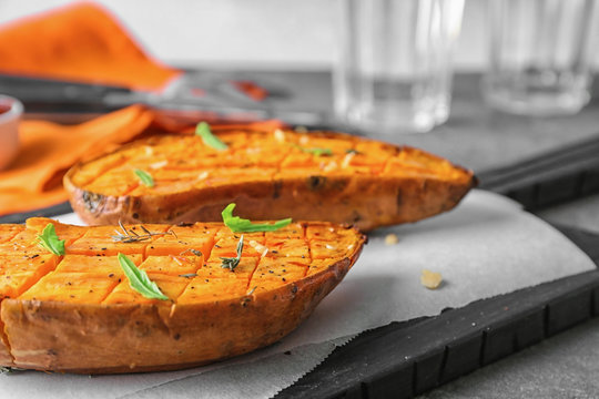 Cutting board with baked sweet potato on table, closeup