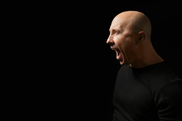 Fototapeta premium Emotional bald man in t-shirt on black background