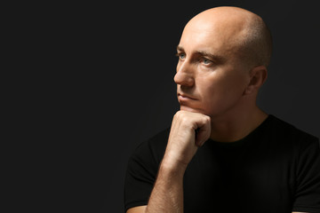 Bald man in t-shirt on black background