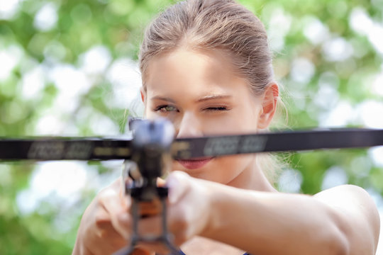 Young woman shooting crossbow outdoors