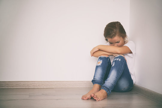 Scared little girl sitting in corner. Domestic violence concept