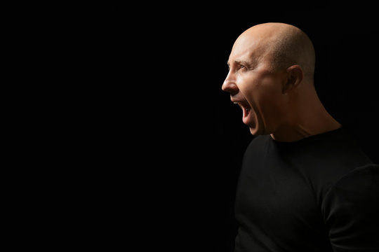 Emotional bald man in t-shirt on black background