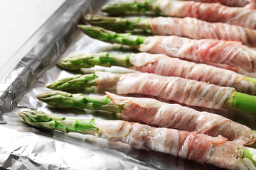 Plate with bacon wrapped asparagus on light background