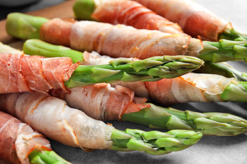 Plate with bacon wrapped asparagus on light background