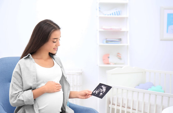 Pregnant woman looking at ultrasound picture at home