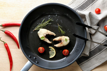 Frying pan with delicious fish steaks on table