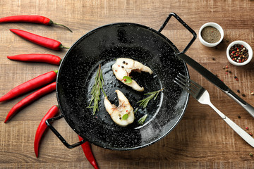 Frying pan with delicious fish steaks on table