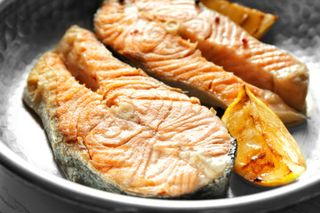 Delicious salmon steaks on frying pan, closeup