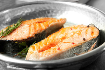 Delicious salmon steaks on frying pan, closeup