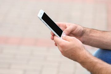 Man holding smartphone outdoors, closeup