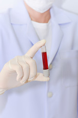 science, chemistry, biology, medicine and people concept - close up of young female scientist holding tube with blood sample making and test or research in clinical laboratory