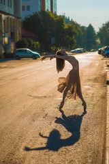 Beautiful, slim girl ballerina dress and Pointe shoes and dancing on the background of the Sunny street the city 