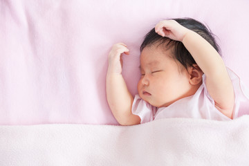 Fototapeta na wymiar Cute asian newborn baby girl sleeping in bed with pink blanket