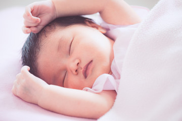 Fototapeta na wymiar Cute asian newborn baby girl sleeping in bed with pink blanket