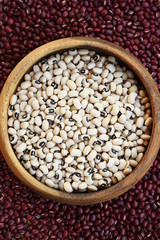 Black eyed peas in wooden bowl on red bean background