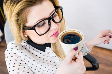 Happy woman at office drinking hot coffee