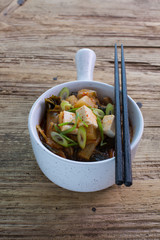 Korean kimchi stew with tofu served in a claypot with a handle. Wooden background, copy space