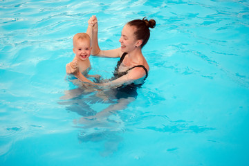 Fototapeta na wymiar Mother teaches to swim an one-year-old kid in pool