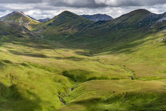 The view of a green valley in Ireland's Connemara National Park with the Twelve Bens Mountains in the background