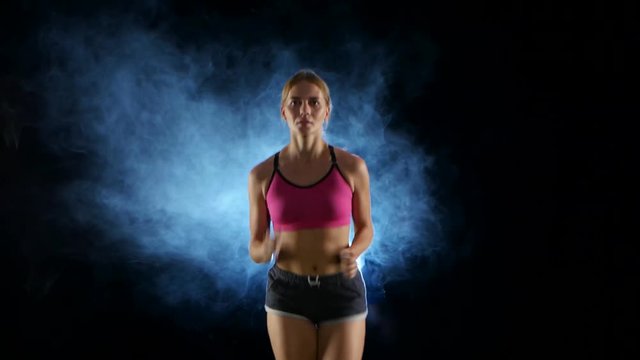 Running sport girl. Front view. Black screen in the smoke. Close up