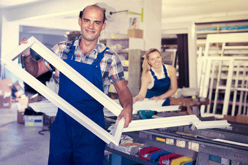Portrait of experienced male worker with plastic window frame
