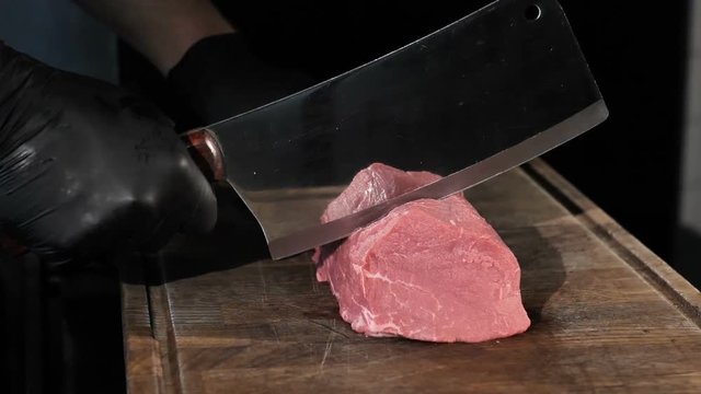 chef chefs cut a piece of meat in black gloves