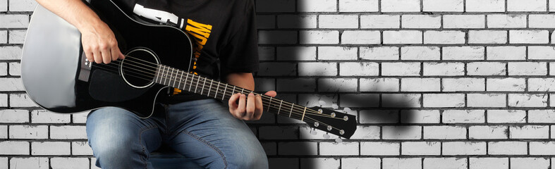 Fototapeta na wymiar Music - Fragment man play a black acoustic guitar