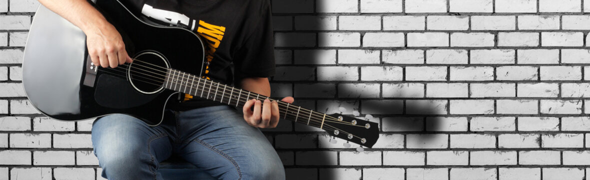 Music - Fragment man play a black acoustic guitar
