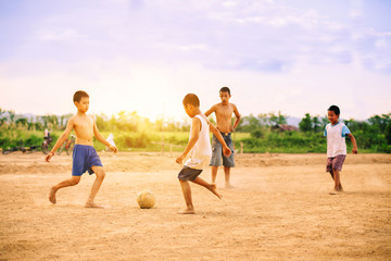 Naklejka premium An action picture of a group of kids playing soccer football for exercise in community rural area.