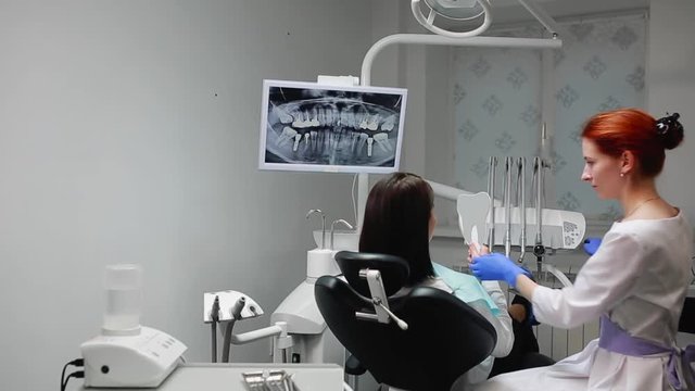 The dentist completes his work with a patient. Removes Bor machine and gives a girl a mirror to assess the work. The girl looks at your teeth and thanked the dentist.