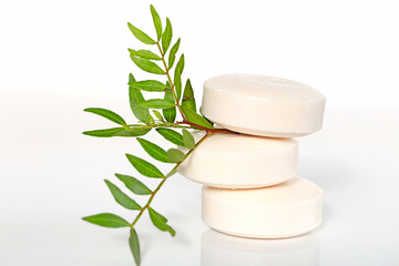 soap with  extract of plants and herbs. three beige round soap in a pile and a green twig on a light background. Organic Cosmetics Concept