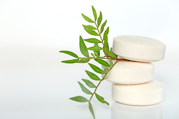 soap with  extract of plants and herbs. three beige round soap in a pile and a green twig . Organic...