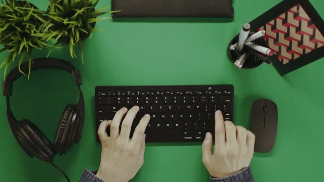 Top down shot of man typing on a keyboard and putting on headphones