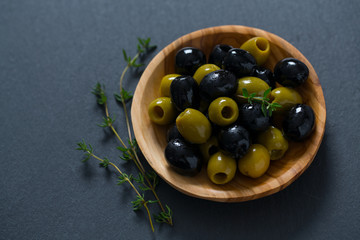 olives in a wooden bowl on black surface