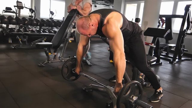 Male bodybuilders working with dumbbells in the gym. A man is working with his hands in the gym.