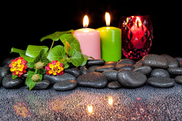 Beautiful spa concept of blooming  flower, candles and black stones