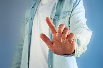 Fototapeta premium Young man touching with his finger an interface on a color background