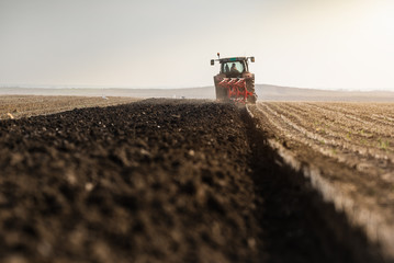 Tractor plowing fields  -preparing land for sowings - obrazy, fototapety, plakaty