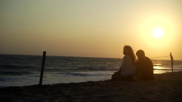  silhouette of young couple in sun light release turtle and siting on the beach at sunset, turtle  sanctuary hatchery located on the beach