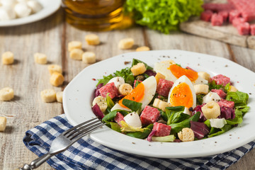 Delicious Italian salad with salami, egg, crostini and mozzarella.