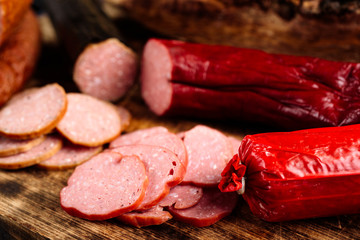 Assortment of sliced delicious smoked sausages on burnt wooden cutting board.