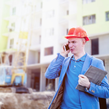 Successful architect man in suit and helmet talking mobile phone on construction site (engineer, construction worker concept)