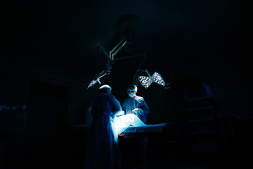 Surgeons do surgery in the dark at operating lamp