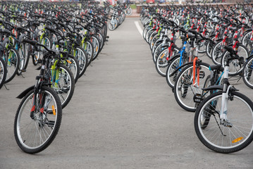 A row of a large number of bicycles with wheels on the town square in summer