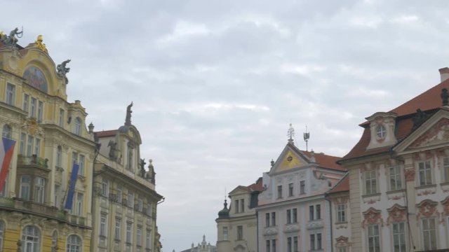 Pan of top of colourful buildings to Jas Hus Statue on Old Town Square in Prague, Czech Republic