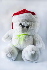 Toy teddy bear wearing Santa hat, on a light background.