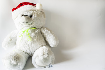 Toy teddy bear wearing Santa hat, on a light background.