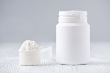 mock up bottle and a spoon with powder, selective focus, on gray